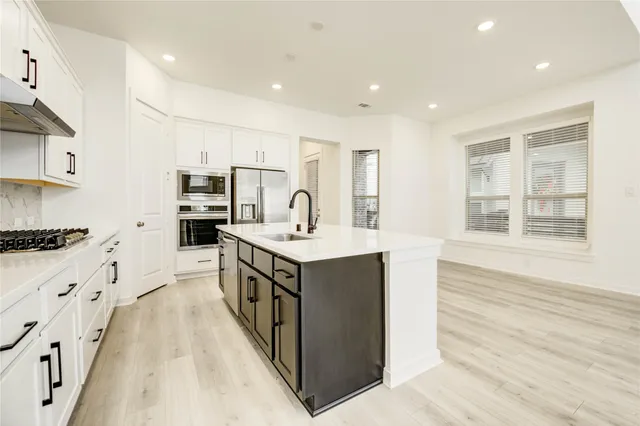 a kitchen with stainless steel appliances kitchen island granite countertop a stove and a sink