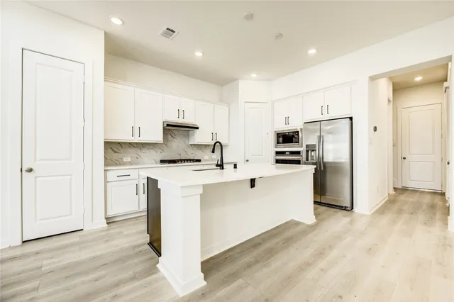 a kitchen with white cabinets and stainless steel appliances