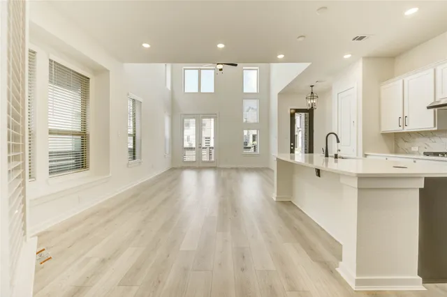 a view of a kitchen with kitchen island a sink wooden floor and a large window