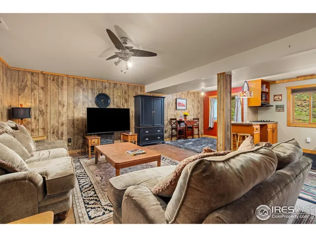 a living room with furniture a flat screen tv and kitchen view
