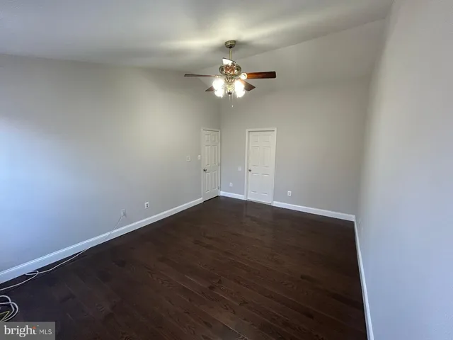 an empty room with wooden floor fan and window