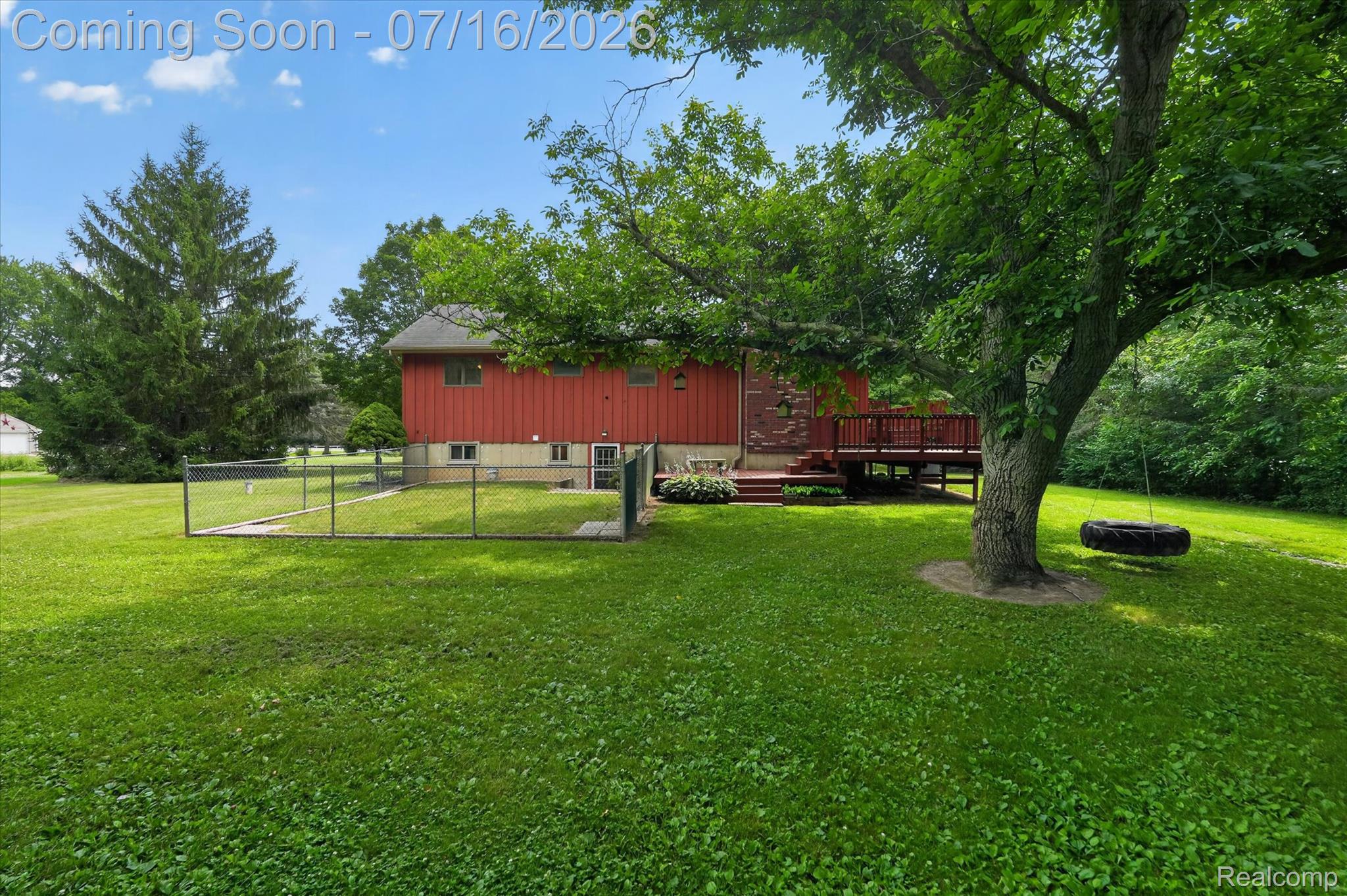11210 Linden Road Linden, MI 48451 - Photo 36 of 61 Expansive green lawn with mature trees and a red-sided residence featuring a multi-level deck