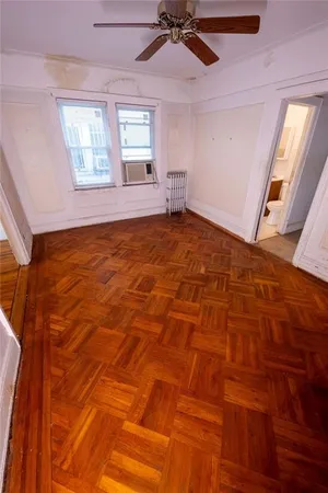 a view of empty room with wooden floor and fan