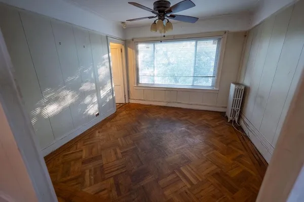 a view of empty room with wooden floor and fan