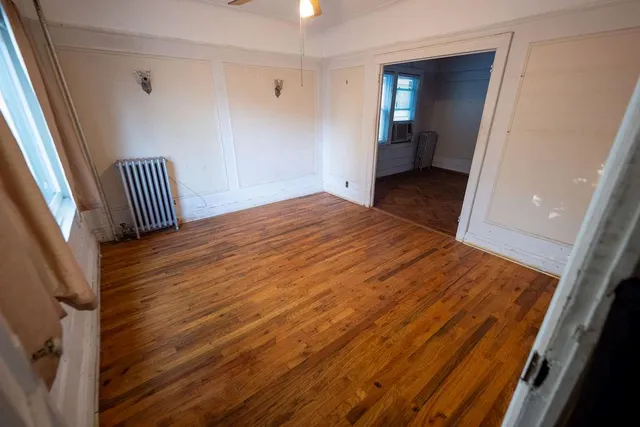 a view of an empty room with wooden floor and a window