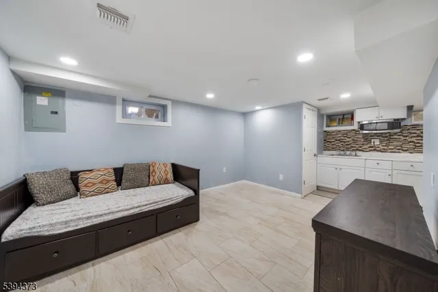 a living room with stainless steel appliances furniture a refrigerator and a coffee table