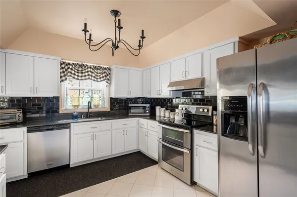 a kitchen with granite countertop a sink stainless steel appliances and white cabinets