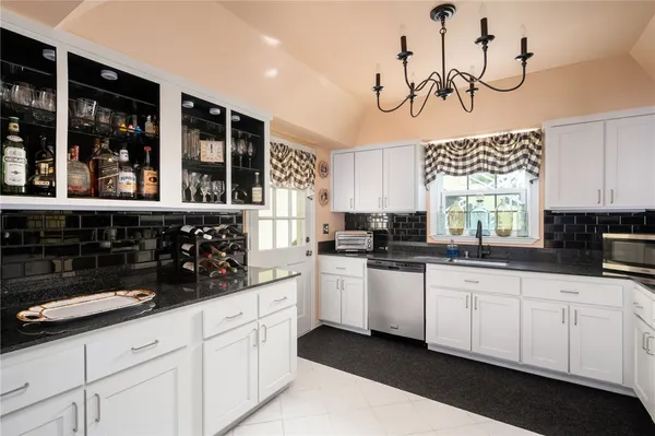a kitchen with white cabinets and window