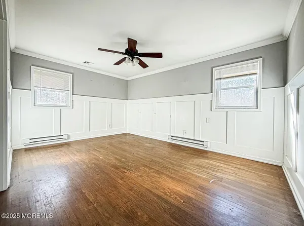 a view of empty room with wooden floor and ceiling fan