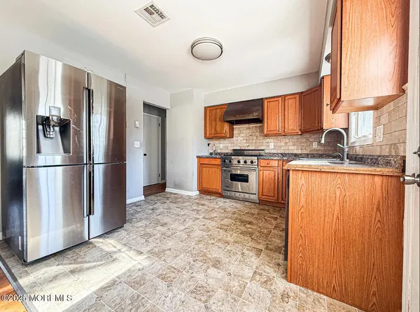 a kitchen with stainless steel appliances granite countertop a refrigerator a stove and a sink