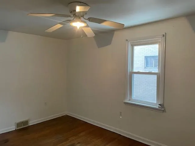 a view of a small space with wooden floor a fan and a window