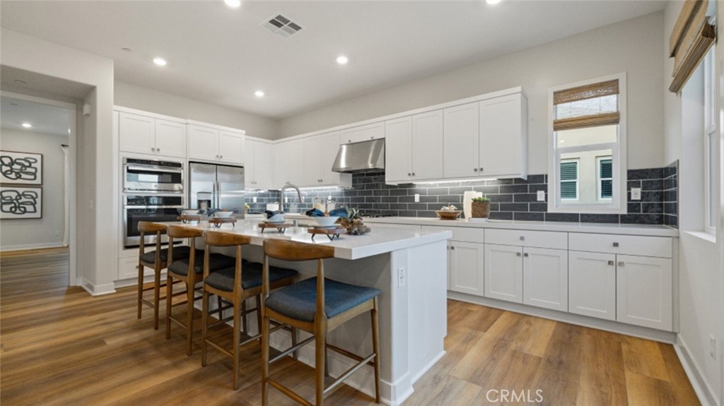 a kitchen with kitchen island granite countertop wooden floor cabinets and dining table chairs