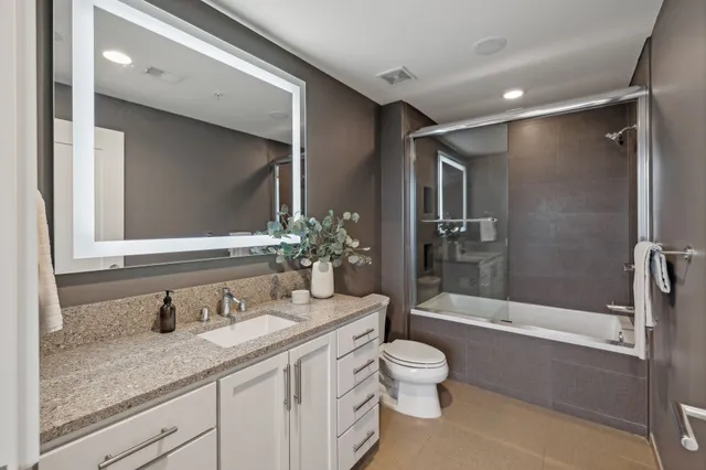a bathroom with a granite countertop sink toilet and shower