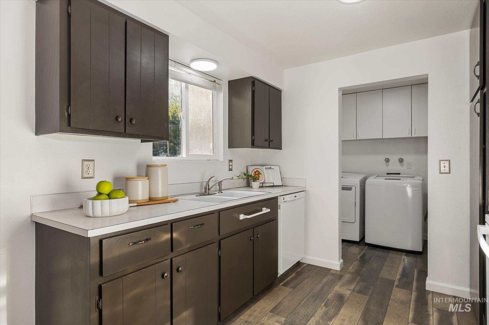 2302 Pendleton Street Boise, ID 83705 - Photo 13 of 35 Kitchen featuring wood-finish flooring, dark cabinetry with hardware, light countertops, and a double basin sink with a window