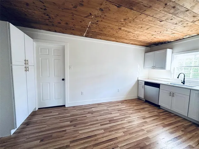 a kitchen with wooden floors and white cabinets
