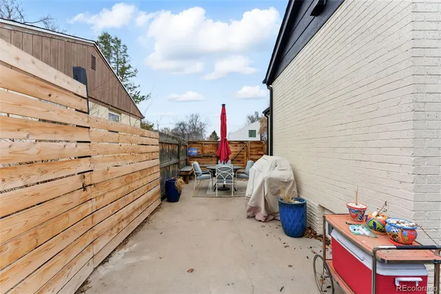 a roof deck with table and chairs and potted plants