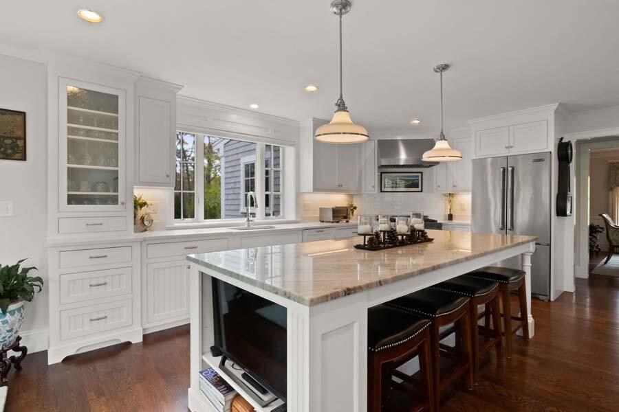 19 Bascom Hollow Harwich, MA 02645 - Photo 11 of 43 a kitchen with a stove a sink dishwasher a dining table and chairs with wooden floor
