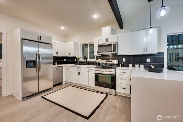 a kitchen with stainless steel appliances kitchen island granite countertop a refrigerator sink and white cabinets