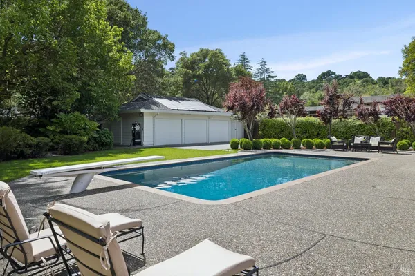 a view of a swimming pool with two chairs in patio