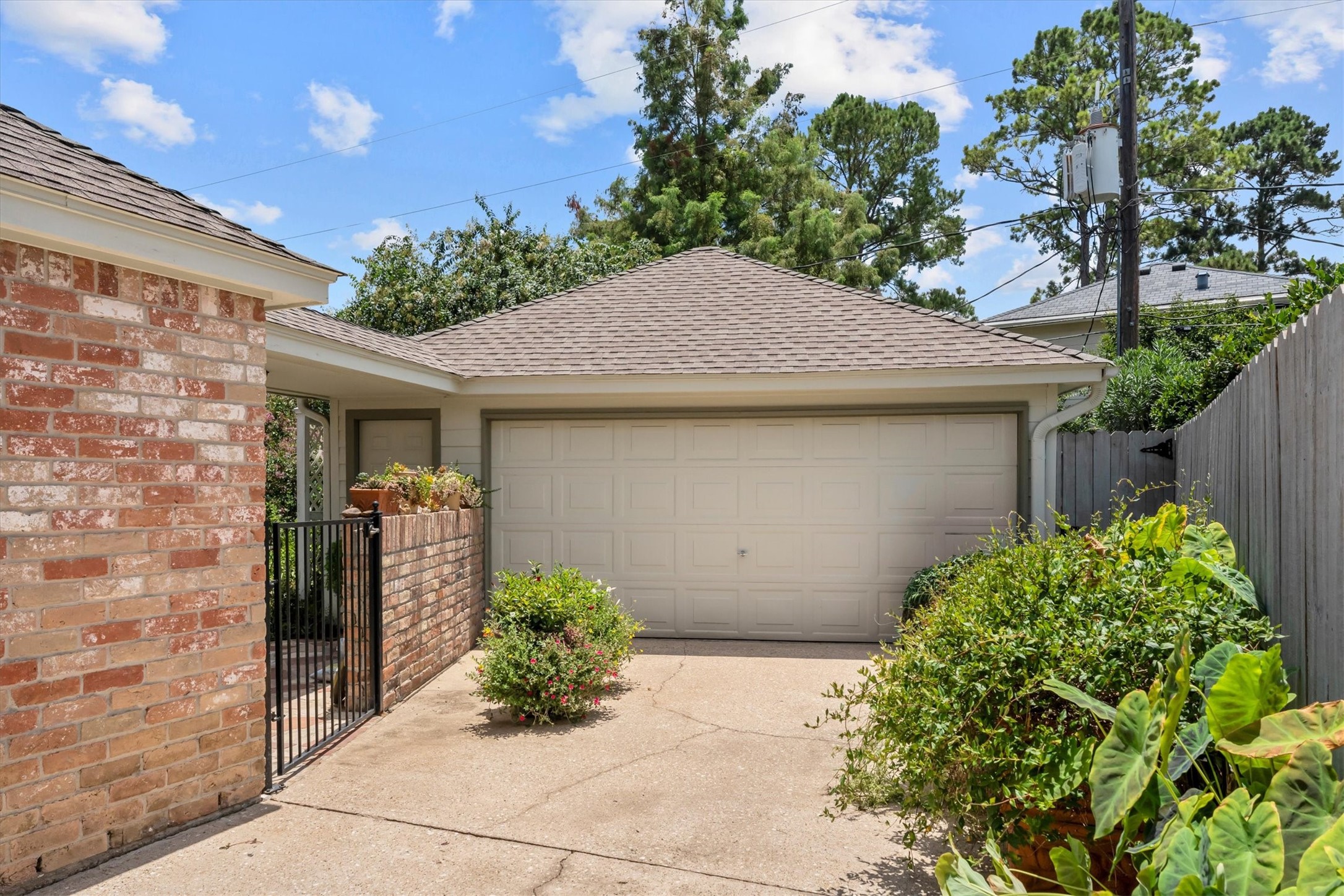 9103 Herts Road Spring, TX 77379 - Photo 41 of 46 A two-car detached garage connects to the home with a covered walkway. The entry to the backyard with wrought iron gate and brick fence adds warmth and interest.