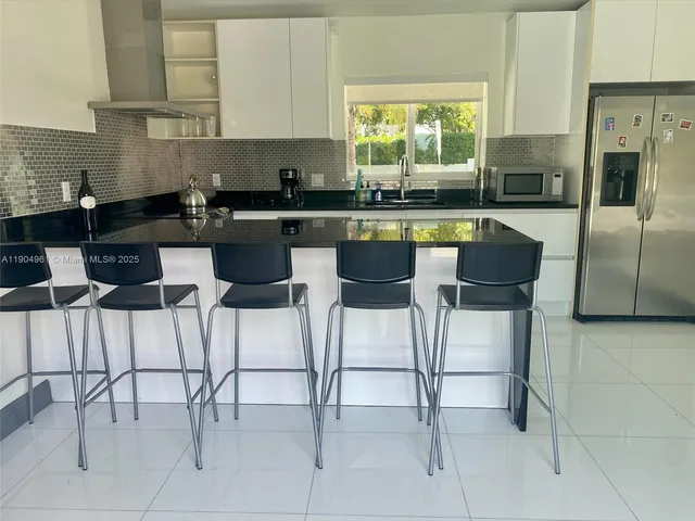 a kitchen with stainless steel appliances granite countertop a table chairs sink and cabinets