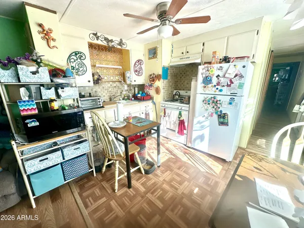 a kitchen with stainless steel appliances a stove a refrigerator a sink a dining table and chairs with wooden floor