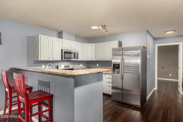 a kitchen with stainless steel appliances granite countertop a refrigerator a stove a sink and dishwasher with wooden floor