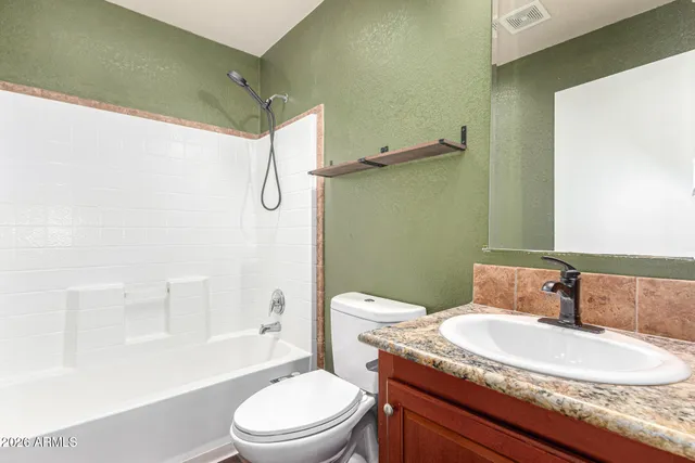 a bathroom with a granite countertop sink toilet a mirror and shower