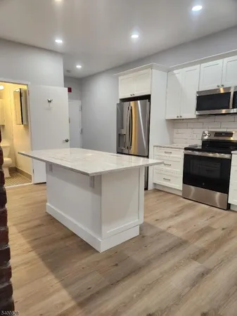 a large kitchen with stainless steel appliances a large counter top a stove a refrigerator and a sink