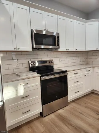 a kitchen with stainless steel appliances white cabinets and a stove a oven with wooden floor