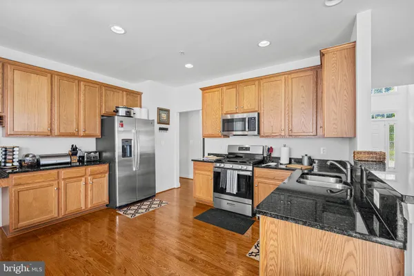 a kitchen with granite countertop a refrigerator stove top oven and sink