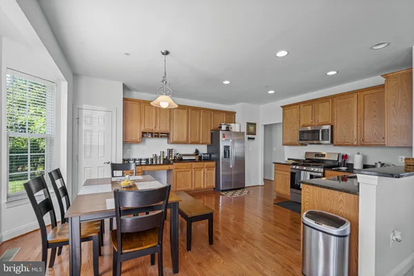 a kitchen with stainless steel appliances a dining table chairs stove refrigerator and cabinets