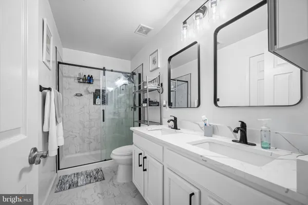 a bathroom with a double vanity sink toilet mirror and shower