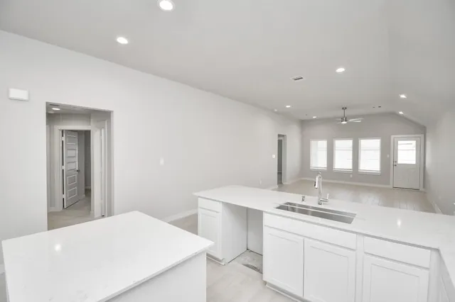 a living room with furniture a rug kitchen view and a table