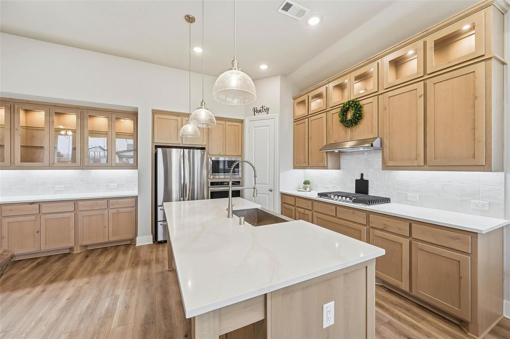 1205 Roundwash Way Midlothian, TX 76065 - Photo 3 of 38 a large kitchen with kitchen island a stove a sink a refrigerator and white cabinets with wooden floor