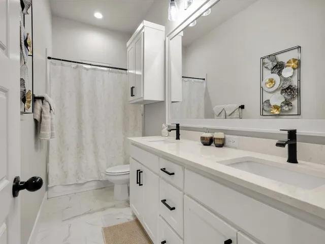 a bathroom with a double vanity sink toilet and shower
