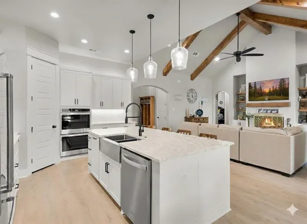 a large white kitchen with lots of counter space and stainless steel appliances