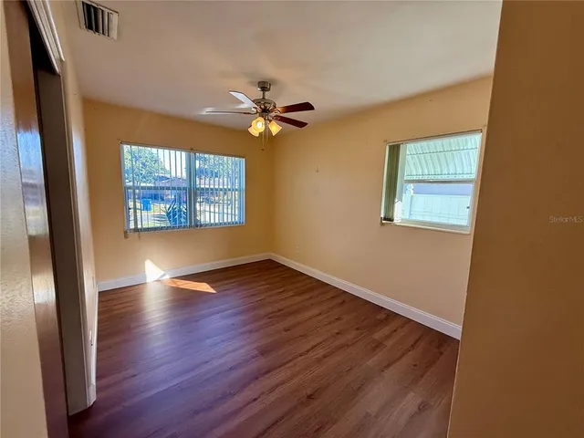 a view of an empty room with a window and wooden floor