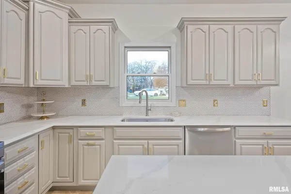a kitchen with white cabinets and sink