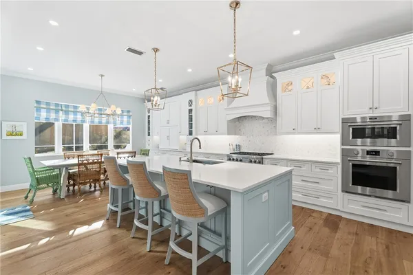 a kitchen with stainless steel appliances granite countertop a stove a refrigerator a kitchen island a dining table and chairs with wooden floor