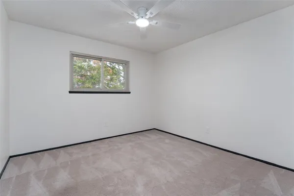 an empty room with a window and a ceiling fan