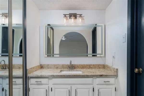 a bathroom with a granite countertop sink and a mirror