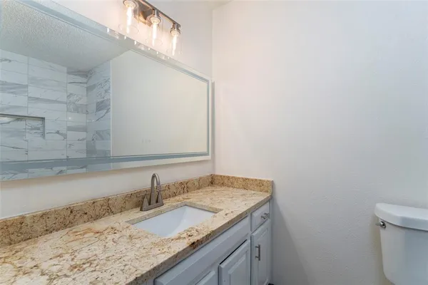 a bathroom with a granite countertop sink and a vanity