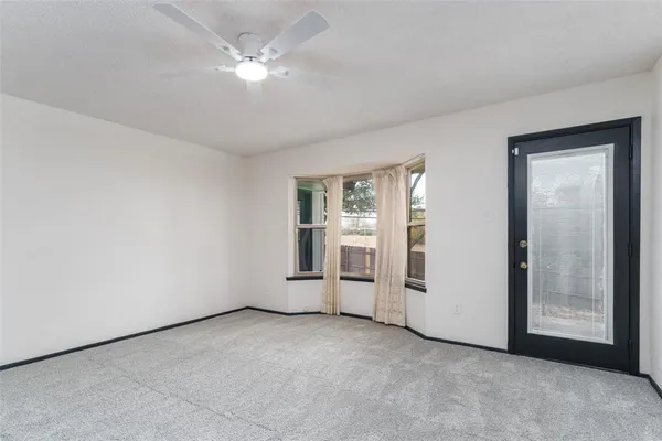 an empty room with chandelier fan and windows