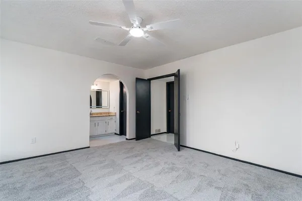 an empty room with chandelier fan and windows