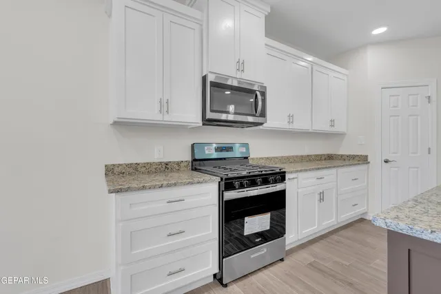 a kitchen with kitchen island granite countertop a sink cabinets and wooden floor