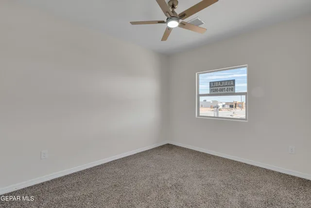 an empty room with a ceiling fan and carpet