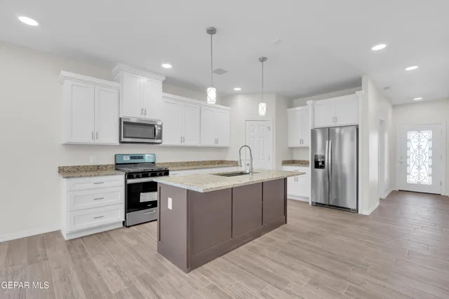 a large kitchen with stainless steel appliances granite countertop a stove a sink dishwasher and a refrigerator with wooden floor