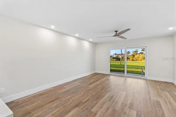an empty room with wooden floor fan and windows