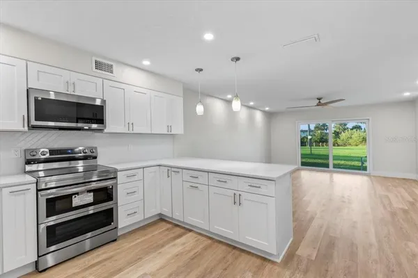 a large kitchen with stainless steel appliances a refrigerator and a wooden floor